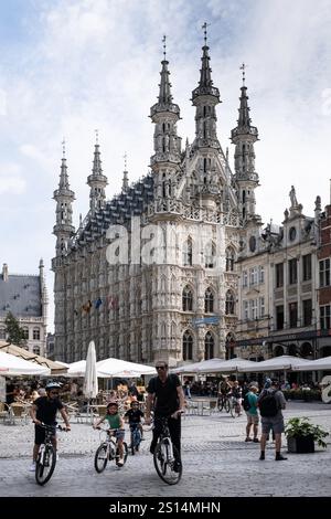 Vater radelt mit seinen Kindern auf dem Groten Markt vor dem alten Rathaus von Löwen Stockfoto