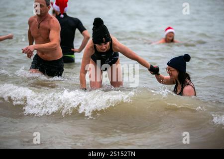 Brighton, Großbritannien. 25. Dezember 2024. Schwimmer am Brighton Beach für Brightons alljährliches Schwimmen am Weihnachtsfeiertag. Mehrere Personen versammelten sich am Weihnachtsmorgen an der Küste für die lange Tradition, die jeden Weihnachtstag um 11:00 Uhr stattfindet. Einige der Schwimmer gingen mit Weihnachtsmützen aufs Meer Stockfoto