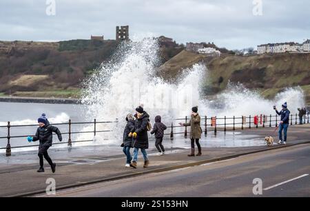 Die Menschen beobachten, wie Wellen in Scarborough, North Yorkshire, abstürzen, da Schnee-, Regen- und Windwarnungen in Kraft sind und voraussichtlich am Silvesterabend Reiseprobleme verursachen werden. Bilddatum: Dienstag, 31. Dezember 2024. Stockfoto