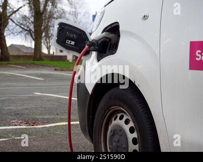 Swinton, Manchester, Großbritannien, 31-12-2024: Aufladen eines elektrischen Transporters an einer öffentlichen Station auf einem Außenparkplatz. Stockfoto