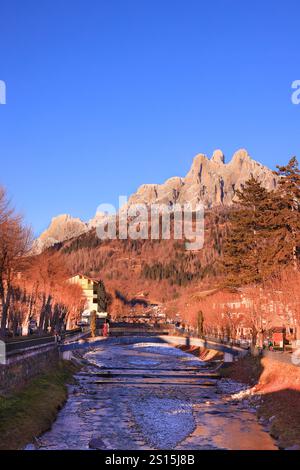 Primiero paese e vista sulle Pale di San Martino durante il tramonto con luci calde e cielo blu Stockfoto