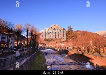 Primiero paese e vista sulle Pale di San Martino durante il tramonto con luci calde e cielo blu Stockfoto