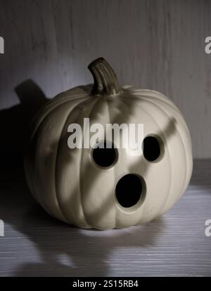 Ein Jack o'Laterne Gesicht hat Angst mit einem Oepn Mund vor einem dunklen Handschatten an einer Wand für eine Angst oder gruselige halloween Nachricht. Stockfoto