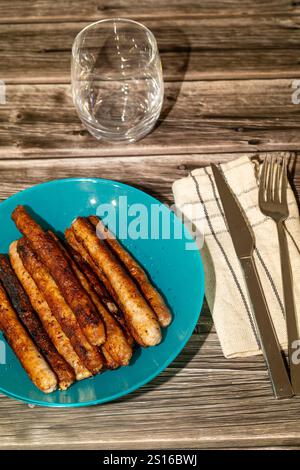 Authentisches Essen mit gebratener Wurst, serviert auf Teller mit Besteck. Deutsches Lebensmittelkonzept Stockfoto