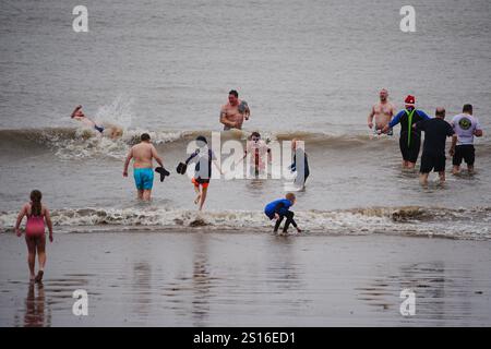 Menschen, die am Strand von Barry Island im Vale of Glamorgan in Südwales spazieren gehen, da Wind-, Regen- und Schneewarnungen in ganz Großbritannien gelten, mit der Gefahr von Überschwemmungen und Störungen der Neujahrsreise. Große Teile Englands und Wales werden bis Mittwoch um 15:00 Uhr von starken Winden getroffen, während Nordwesten Englands und Wales voraussichtlich einen Großteil des morgens starken Regen erleben werden. Bilddatum: Mittwoch, 1. Januar 2025. Stockfoto