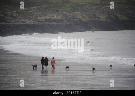 Menschen, die am Strand von Barry Island im Vale of Glamorgan in Südwales spazieren gehen, da Wind-, Regen- und Schneewarnungen in ganz Großbritannien gelten, mit der Gefahr von Überschwemmungen und Störungen der Neujahrsreise. Große Teile Englands und Wales werden bis Mittwoch um 15:00 Uhr von starken Winden getroffen, während Nordwesten Englands und Wales voraussichtlich einen Großteil des morgens starken Regen erleben werden. Bilddatum: Mittwoch, 1. Januar 2025. Stockfoto