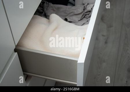 Nahaufnahme von warmen Stricktüchern, gefaltet in einer weißen Kommode Stockfoto