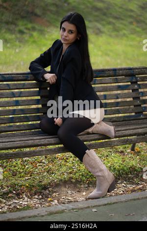 Modische Geschäftsfrau, die eine Pause in einem Park macht und die frische Luft und die herbstliche Landschaft genießt Stockfoto