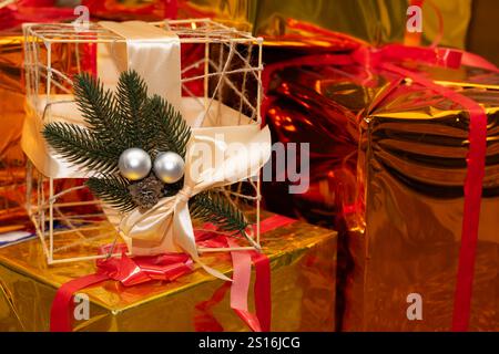 Farbenfrohe Geschenke in glänzendem Papier sorgen für eine festliche Atmosphäre. Ein Geschenk mit Schleife und immergrünen Akzenten verleiht dem di eine charmante Note Stockfoto