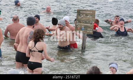 Jena, Deutschland. Januar 2025. Mehrere hundert Badefreunde schwimmen am Neujahrstag im Schleichersee bei einer Lufttemperatur von 6 Grad und einer Wassertemperatur von rund 4 Grad. Zum fünften Mal lud die Jenaer Bäder- und Freizeitgesellschaft 2025 zum gemeinsamen Schwimmen im Südbad ein. Quelle: Bodo Schackow/dpa/Alamy Live News Stockfoto