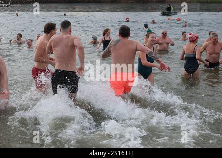 Jena, Deutschland. Januar 2025. Mehrere hundert Badefreunde schwimmen am Neujahrstag im Schleichersee bei einer Lufttemperatur von 6 Grad und einer Wassertemperatur von rund 4 Grad. Zum fünften Mal lud die Jenaer Bäder- und Freizeitgesellschaft 2025 zum gemeinsamen Schwimmen im Südbad ein. Quelle: Bodo Schackow/dpa/Alamy Live News Stockfoto