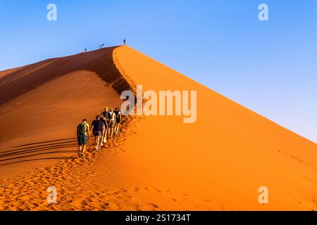 SESRIEM, NAMIBIA - 21. AUGUST 2024: Familie mit Rucksäcken Klettern Dune 45 Stockfoto