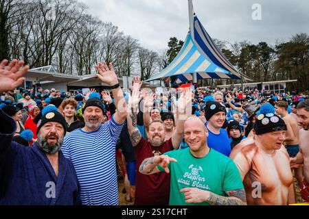 Haltern, Deutschland. Januar 2025. Teilnehmer, viele in Kostümen, haben Spaß beim jährlichen Neujahrsschwimmen am Haltern See in der Nähe der Stadt Haltern am See. Fast 700 registrierte Teilnehmer, ein Rekord für die Veranstaltung, laufen über den natürlichen Sandstrand des Sees lido und ins eiskalte Wasser, um ein Bad zu nehmen und für wohltätige Zwecke zu schwimmen (dieses Jahr eine Suppenküche für Bedürftige). Mehrere hundert weitere sind gekommen, um die Schwimmer zu beobachten, die sich anschließend mit Tee, Glühwein und herzhaftem Essen am Strand aufwärmen. Quelle: Imageplotter/Alamy Live News Stockfoto