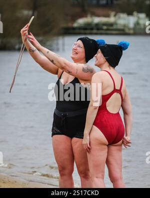 Haltern, Deutschland. Januar 2025. Schwimmer machen Selfies. Teilnehmer, viele in Kostümen, haben Spaß beim jährlichen Neujahrsschwimmen am Haltern See in der Nähe der Stadt Haltern am See. Fast 700 registrierte Teilnehmer, ein Rekord für die Veranstaltung, laufen über den natürlichen Sandstrand des Sees lido und ins eiskalte Wasser, um ein Bad zu nehmen und für wohltätige Zwecke zu schwimmen (dieses Jahr eine Suppenküche für Bedürftige). Mehrere hundert weitere sind gekommen, um die Schwimmer zu beobachten, die sich anschließend mit Tee, Glühwein und herzhaftem Essen am Strand aufwärmen. Quelle: Imageplotter/Alamy Live News Stockfoto