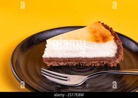 Eine einzelne Portion eines tiefgefüllten New Yorker Käsekuchens. Der Kuchen wird mit einer Backgabel serviert Stockfoto