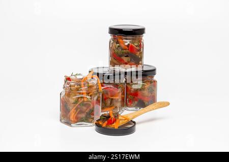 Gläser mit hausgemachtem eingelegtem Gemüse mit Holzlöffel auf weißem Hintergrund Stockfoto