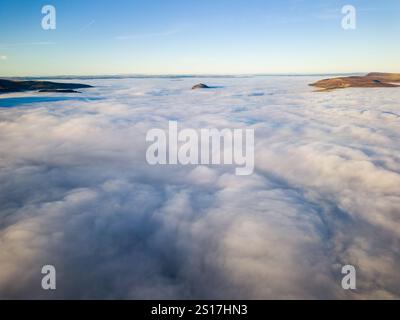 Aus der Vogelperspektive auf ein Nebelmeer, das ländliche Täler und Ackerland bedeckt Stockfoto