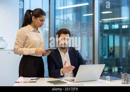 Business Team Mann und Frau zusammen in der Mitte des Büros, diskutieren über neue Startups, Mann und Frau in Geschäftskleidung reden und diskutieren, arbeiten mit einem Laptop. Stockfoto