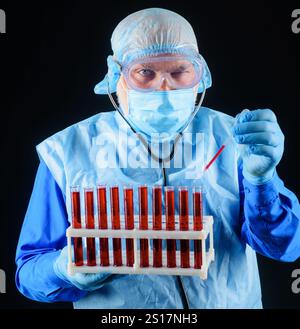 Bluttest. Arzt in Handschuhen, die mit Blutproben des Patienten arbeiten. Serologische Testung im Krankenhaus. Medizinwissenschaftler oder Laboratoriumsassistent in Maske Stockfoto