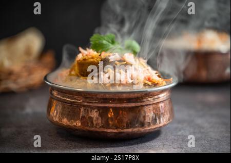 Rauchig scharfer indischer Biryani-Pulao in goldener Schüssel mit indischem Basmati-Reisgericht mit Hühnerfleisch-Curry Ramadan Kareem, Eid. Servierschüssel aus Messing mit Weißwein Stockfoto