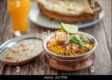 Würziger indischer Biryani-Pulao in goldener Schüssel mit indischem Basmati-Reisgericht mit Hühnerfleisch-Curry Ramadan Kareem, Eid. Servierschale aus Messing mit weißem Rücken Stockfoto