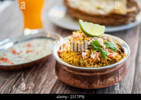 Würziger indischer Biryani-Pulao in goldener Schüssel mit indischem Basmati-Reisgericht mit Hühnerfleisch-Curry Ramadan Kareem, Eid. Servierschale aus Messing mit weißem Rücken Stockfoto