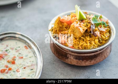 Würziger indischer Biryani-Pulao in goldener Schüssel mit indischem Basmati-Reisgericht mit Hühnerfleisch-Curry Ramadan Kareem, Eid. Servierschale aus Messing mit weißem Rücken Stockfoto