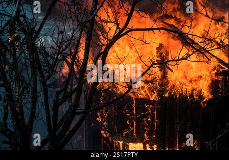 Ein Haus, das in Flammen steht und abbrennt. Völlig verschlungen. Feuer im Haus. Hausfeuer in der Nacht. Einfamilienhaus komplett zerstört Stockfoto