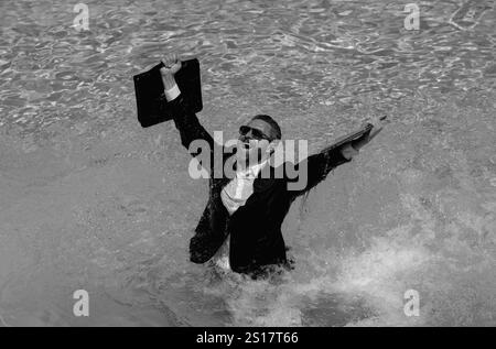 Verrücktes Sommergeschäft. Unterhaltsamer Geschäftsleben. Komischer, verrückter Geschäftsmann im Anzug, der ein Notebook im Poolwasser benutzt. Ein lustiger Geschäftsmann. Freiberufliches Konzept, verrückt Stockfoto