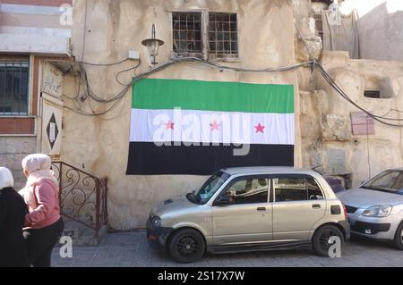 Damaskus Sham, Syrien. Januar 2025. Eine neue syrische Flagge an einer Mauer des alten Damaskus, Syrien, 1. Januar 2025. Seit dem Sturz des Regimes von Baschar al Assad am 8. Dezember 2024 verbreitet die neue Regierung überall im Land neue syrische Flaggen mit drei Sternen, da die Symbole von Assads Regime zerstört wurden. (ELISA Gestri/ Credit: SIPA USA/Alamy Live News Stockfoto