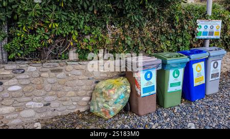 Vier bunte Müllsortierbehälter und eine gelbe Tüte am Strand. Umweltschutz. Denken Sie anders. September 2024. Pomonte, Stockfoto