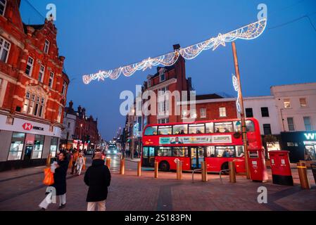 Bromley, London, Großbritannien - 28. Dezember 2024: Abendlichter mit historischer Architektur und rotem Doppeldeckerbus während der Festtage Stockfoto