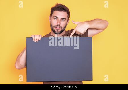 Mann mittleren Alters mit leerem Plakat. Darstellung des Kopierbereichs für Ihren Text oder Ihr Design. Ein Mann, der eine leere Werbetafel im Studiohintergrund zeigt. Blan Stockfoto
