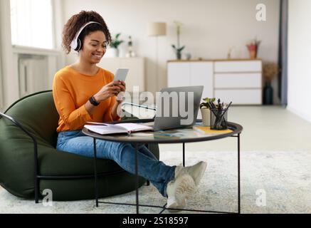 Lächelnde schwarze Frau mit schnurlosem Kopf und Mobiltelefon Stockfoto