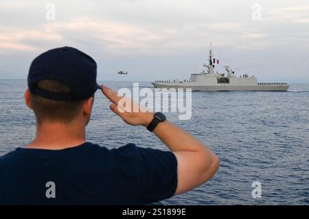 Ein Besatzungsmitglied an Bord der Küstenwache Cutter Eagle (WIX 327) würdigt während einer Überlebenszeremonie mit dem französischen Marineschiff FS Guépratte (F714) in der Karibik am 7. Juni 2024. Die Guépratte, das französische Marineschiff FS Tonnerre (L9014) und die Eagle hatten kürzlich Cartagena in Kolumbien verlassen. (Foto der US-Küstenwache von Petty Officer 1st Class Matthew West) Stockfoto