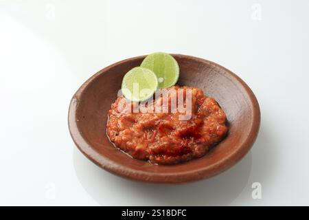 Sambal Tomate oder scharfe Tomatenpaste auf Tonplatte, mit Limette Stockfoto