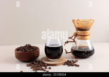 Chemex Glaskaffeemaschine mit leckerem Tropfkaffee und Bohnen auf Creme-Tisch, Kopierraum für Text Stockfoto