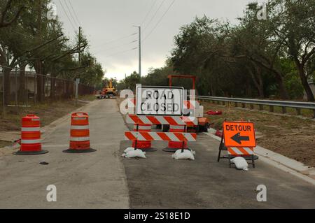 Weitsicht Schwarzes und weißes Straßenschild mit geschlossenem Schild und orangefarbenem Umleitungsschild. Wasserreparatur auf einer großen Baustelle. Orangenkegel und Fass mit Leadi Stockfoto