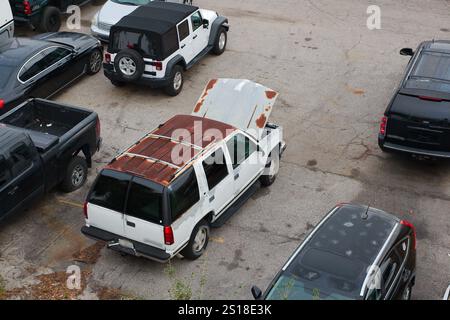 Hohe Aussicht über einen alten weißen, rostigen SUV auf einem Parkplatz mit anderen Autos, kein Platz für Leute zum Kopieren. Stockfoto