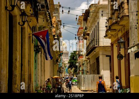 Foto einer Straße in Havanna, die zum Capiitolio führt, zeigt eine kubanische Flagge, koloniale Architektur und lebendige Kultur. Stockfoto