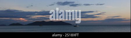 Katamaran und Ko Khlum, kleine Insel mit Blick auf den Sonnenuntergang vom Strand Klong Kloi, Koh Chang, Thailand. Stockfoto