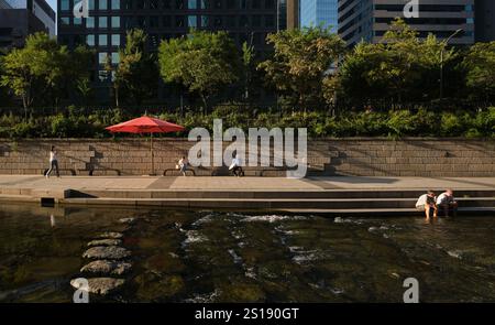 Ein roter Regenschirm und der Fußweg am Ufer des Flusses. Entlang des von Cheonggyecheon wiedergewonnenen Flussparks in Seoul, Südkorea. Stockfoto