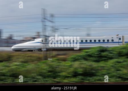 Der japanische Nozomi Shinkansen verlässt den Bahnhof Nagoya. Die Räder sind im Unterwagen sichtbar und werden durch Bewegungsunschärfe zur Betonung der Geschwindigkeit aufgenommen. Stockfoto