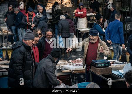 Catania, Italien - 30. Dezember 2024: Lokale Fischhändler und Kunden interagieren auf dem belebten „La Pescheria“, Catanias berühmtem Fischmarkt in der Nähe der Piazza Stockfoto