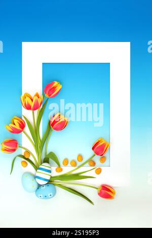 Osterdekor und Mini-Eier mit Frühlingstulpenblüten. Abstraktes Rahmendesign auf blauem Hintergrund mit Farbverlauf, weißem Rahmen, saisonalen Symbolen für Urlaub Stockfoto