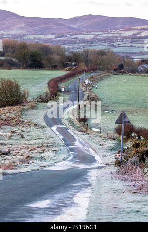 Ein starker Frost entlang einer mäandernden Landstraße im Dorf Moel-y-Crio mit den Hügeln der Clwydian Range in der Ferne, Flintshire North Wales mit einer Met Office Yellow Warnung für Eis und eine weitere Warnung am Wochenende für Schnee. Januar 2025, Flintshire, Wales ©DGDImages/Alamy Live News Stockfoto