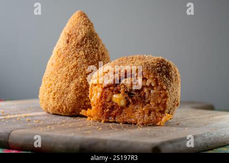 Authentische sizilianische Arancino (oder Arancina) auf einem rustikalen Holzbrett mit knusprigem Äußere und reichhaltiger Fleischfüllung, perfekt für Tradition Stockfoto