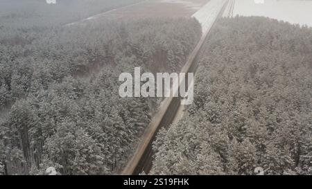 Landschaft einer Winterstraße in einem Nadelwald. Autobahn durch die Kiefern. Das Auto fährt auf einer Winterstrecke durch einen Nadelwald. Stockfoto