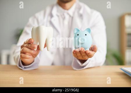 Zahnarzt sitzt in der Zahnklinik und hält Schweinebank und gesunden weißen Zahn in den Händen. Stockfoto