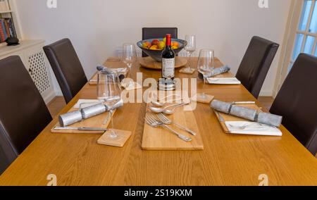 Esstisch Set für Weihnachtsessen mit Weihnachtskräckern, Flasche edlen Wein und Weingläsern, UK Stockfoto